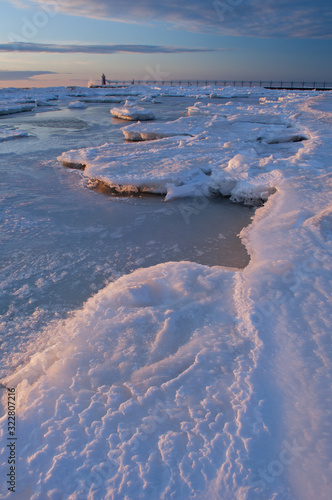 Winter  South Haven  Michigan Lighthouse with splashing wave and frozen shoreline at sunset  Lake Michigan  USA