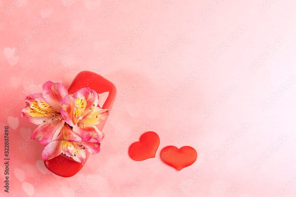 Flowers alstroemeria in red vase and two red textile hearts on pink hearts bokeh background. Valentines day festive background. Top view, flat lay, copy space for text.