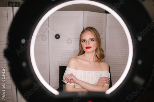 Young beautiful model posint for photo. Attractive young woman sitting in the beauty studio. Background of white folding screen