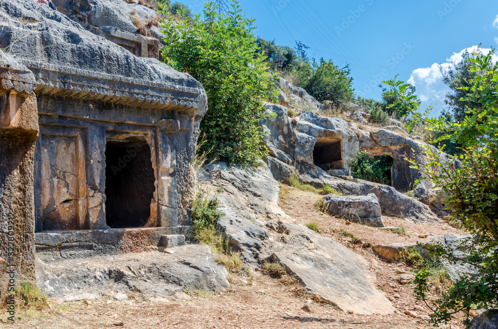 Ancient cemetery in the city of Limyra, Turkey. The entrance to the old concrete tomb in the rock. Excursion to the historical monument of architecture. Burial of ancestors closer to the sky