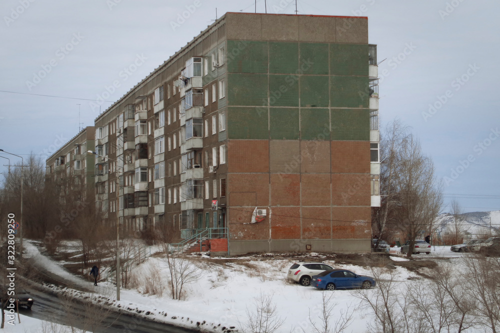 Soviet apartment building. Apartment block. Soviet architecture. Ust-Kamenogorsk (Kazakhstan). Concrete apartment building. Dark. Hill. Winter snow. Plattenbau. Street cars people
