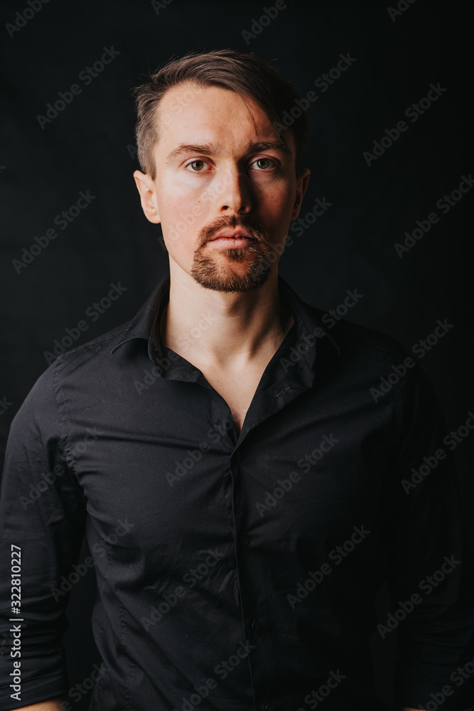 Handsome man. Photo in a photo studio on a black background. A young man expresses his emotions with expressions, gesticulation and attitude.