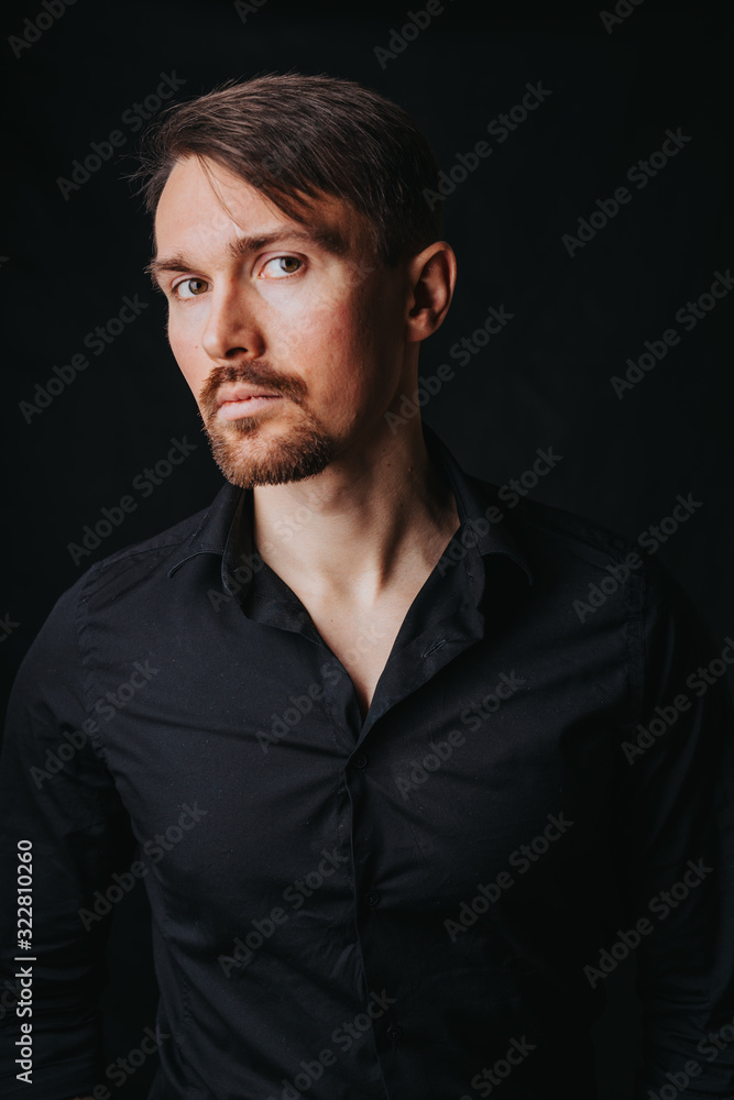 Handsome man. Photo in a photo studio on a black background. A young man expresses his emotions with expressions, gesticulation and attitude.