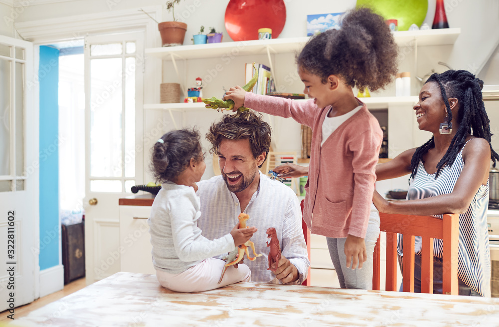 Young family playing with toy dinosaurs in kitchen Young family playing with toy dinosaurs in kitchen