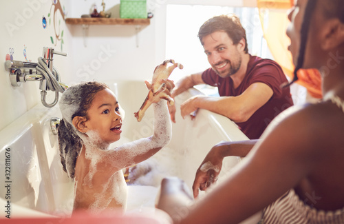 Parents giving daughter bubble bath photo