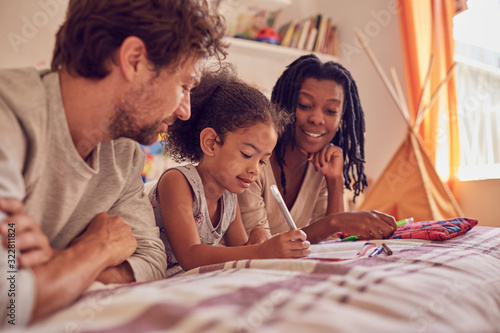 Young family coloring on bed