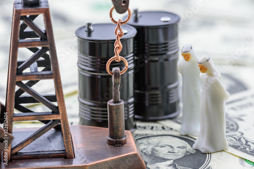 Crude oil price and petroleum demand concept :  Arab men in white thawbs negotiate on a trade deal or buying contract. Oil rig or pumpjack and black crude oil drum barrels on US USD dollar banknotes. photo