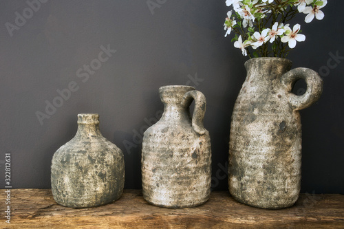 White flowers in concrete rustic pots near dark grey wall, modern design © annebel146