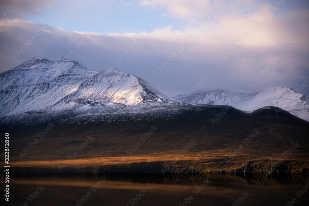 Beautiful snow mountain in Husavik, Iceland with warm light of sunset, beautiful cloud and sky as well as reflection of water and mountain. Idea for any backgrounds used. Beautiful snow mountain in Husavik, Iceland with warm light of sunset, beautiful cloud and sky as well as reflection of water and mountain. Idea for any backgrounds used.