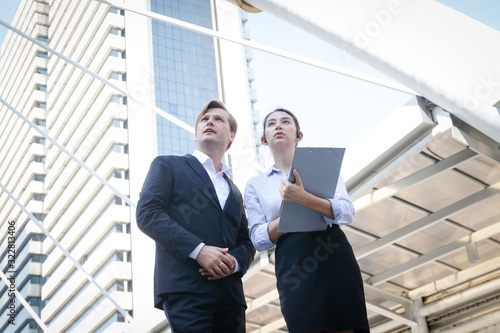 Male and female businessmen from different nationalities stand meeting outside the building. Entrepreneurial concept © SUPERMAO