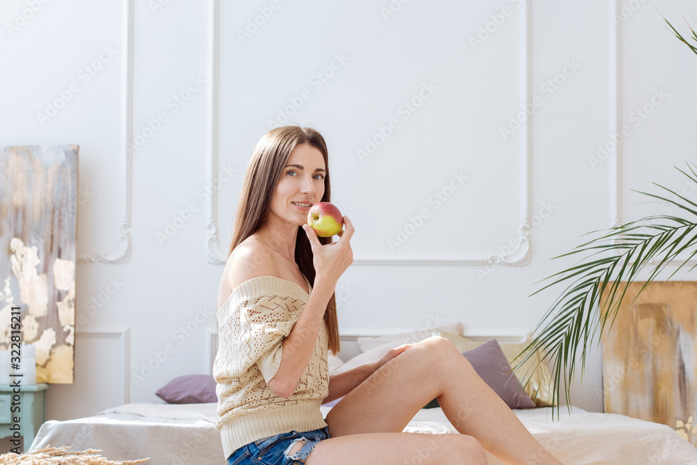 Beautiful healthy lifestyle picture of woman with red apple in boho light interior Beautiful healthy lifestyle picture of woman with red apple in boho light interior
