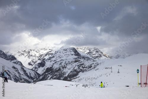 Snowy ski slope with skier and snowboarder in high mountains photo