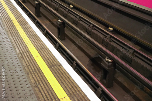 Detail on dirty rails near platform in London underground tube station