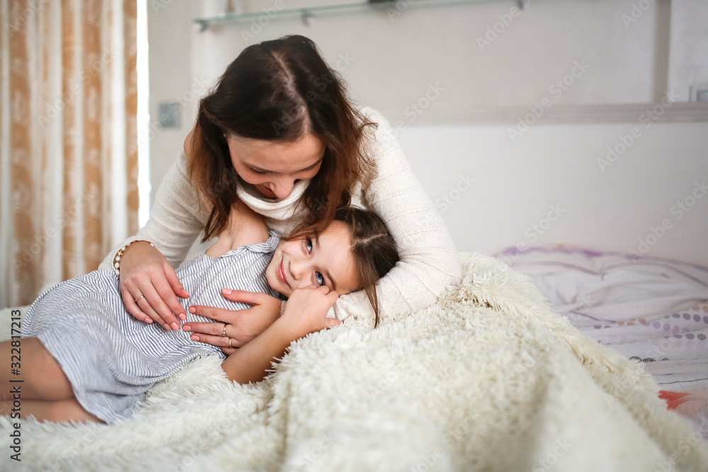 Tender Caucasian mom and daughter hugging on bed Tender Caucasian mom and daughter hugging on bed