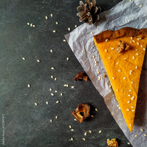 A piece of pumpkin cheesecake on white crumpled paper on a black granite chalkboard with text space