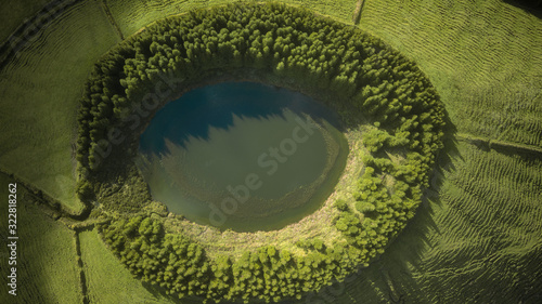 Drone aerial view of "Lagoa do Pau Pique" lagoon surrounded by green forest located on Sao Miguel, Azores, Portugal.