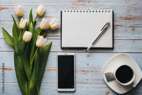 Fototapeta Naklejka Na Ścianę i Meble -  White bouquet of tulips on wooden background with coffee Cup, smartphone and empty notebook