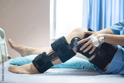 Asian woman patient with bandage compression knee brace support injury on the bed in nursing hospital.healthcare and medical support. photo