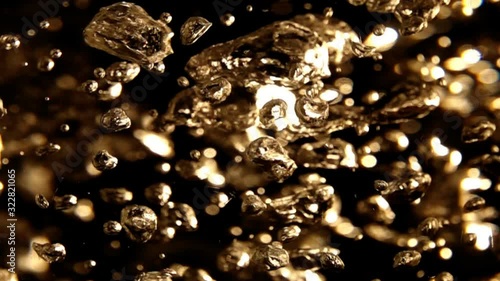 Slow Motion Video: The chaotic slow motion of air bubbles inside boiling water. Abstract golden background with moving and vibrating volume bubbles, blurry spots and bright highlights