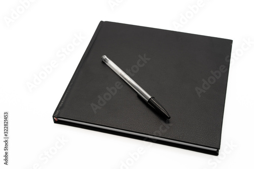 Cuaderno negro de tapa dura con bolígrafo negro sobre fondo blanco