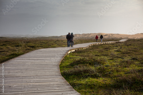Corrubedo Natural Park, Galicia, Spain: People walking along the wooden path that gives access to the large dune, the main attraction of the park. photo