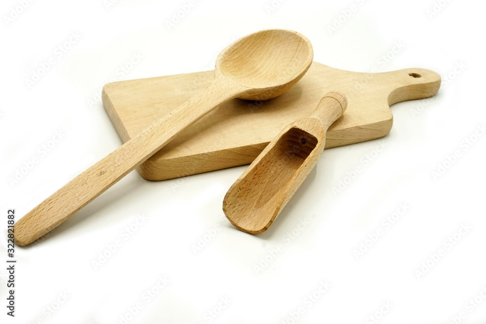 Wooden kitchen utensils on white background. Cutting board, spoon and scoop.