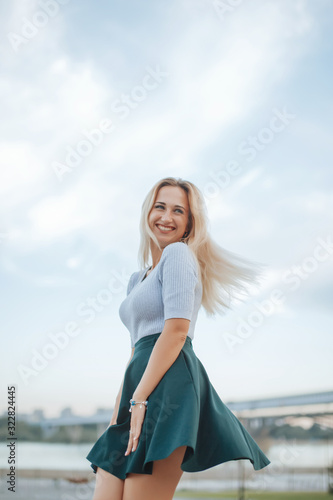 Fotografie Woman twirling her skirt in summer on sky background