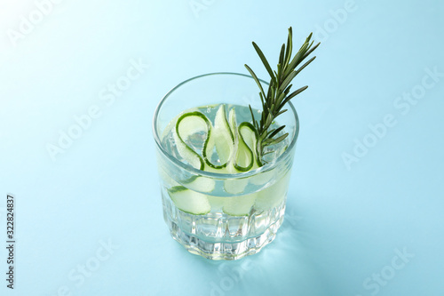 Glass with infused cucumber water on blue background, close up