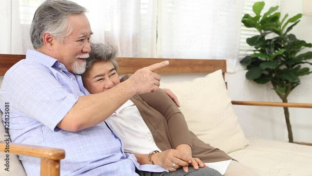 Asian senior couple smiling on a sofa in the house Asian senior couple smiling on a sofa in the house