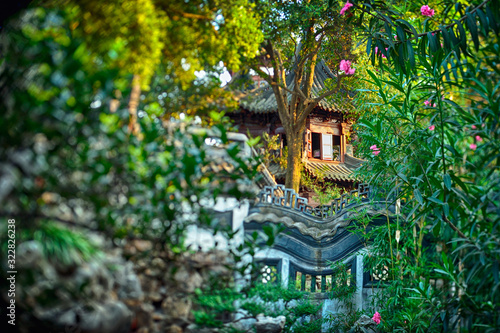 Beautiful Chinese style traditional wooden building hidden in the middle of lush vegetation. Selective focus effect obtained in camera with special lens.