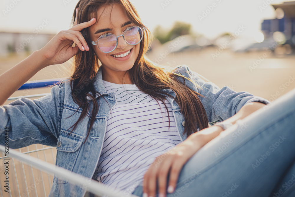 Cheerful woman resting in shopping cart