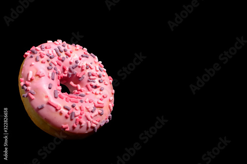 flying donut on black background. Unhealthy food concept. Sweet pink iced doghnut photo