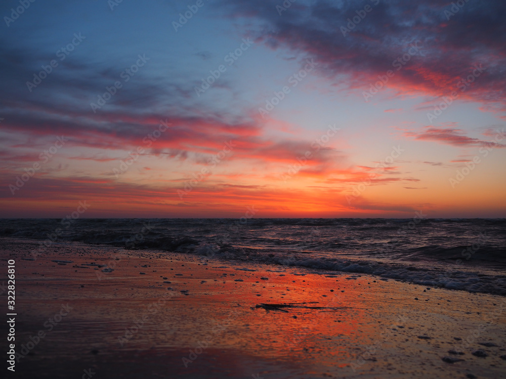 The waves wash the sandy beach at sunrise