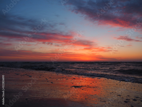 The waves wash the sandy beach at sunrise