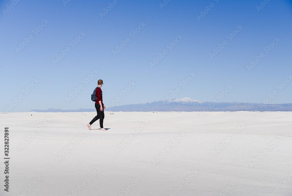 A man walking across sand dunes. 