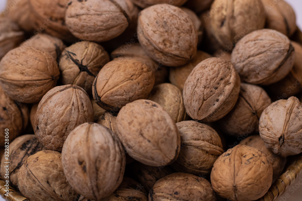 Walnuts on a white background in a small wicker basket. A lot of walnuts. Close-up Walnuts on a white background in a small wicker basket. A lot of walnuts. Close-up