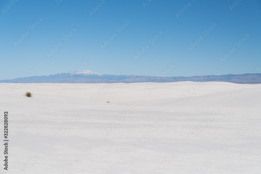 A snow capped mountain peak in the background of White Sands in New Mexico. 