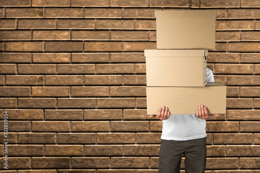 Delivery man carrying stacked cardboard boxes in front of face - obrazy, fototapety, plakaty 