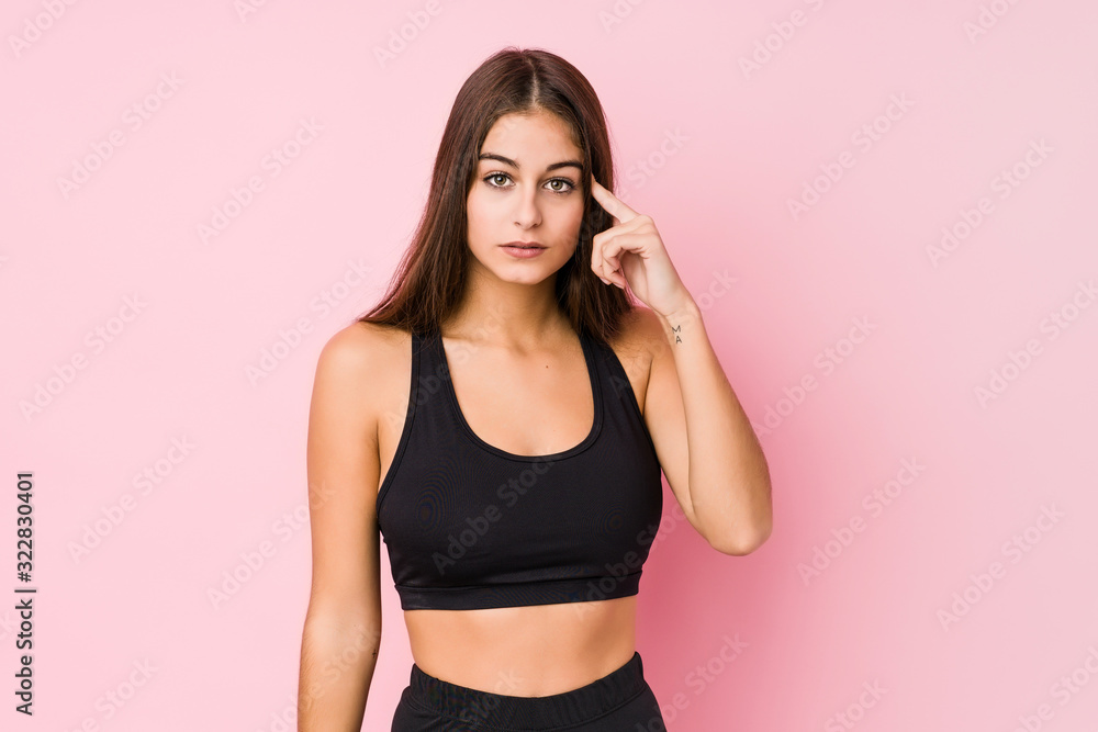 Young caucasian fitness woman doing sport isolated pointing temple with finger, thinking, focused on a task. Young caucasian fitness woman doing sport isolated pointing temple with finger, thinking, focused on a task.