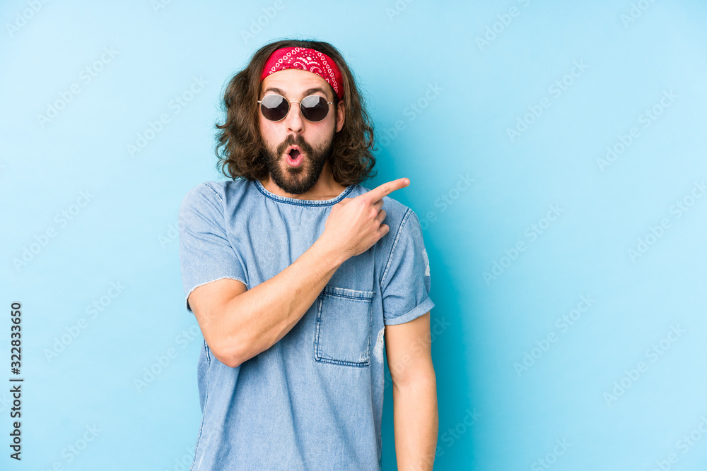 Young long hair man wearing a festival hipster look isolated pointing to the side Young long hair man wearing a festival hipster look isolated pointing to the side
