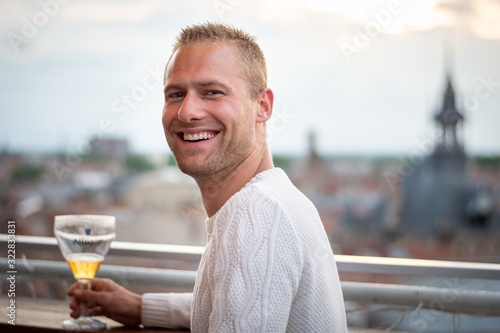 Portrait beau gosse charmant jeune homme caucasian blond aux yeux bleu joyeux et confiance en soi séduisant chanceux charismatique européen heureux zen à motivation rooftop toulouse