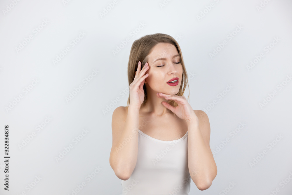 young beautiful blond woman looks happy satisfied with her skin touching her face standing with closed eyes on isolated white background, healthcare and beauty concept young beautiful blond woman looks happy satisfied with her skin touching her face standing with closed eyes on isolated white background, healthcare and beauty concept