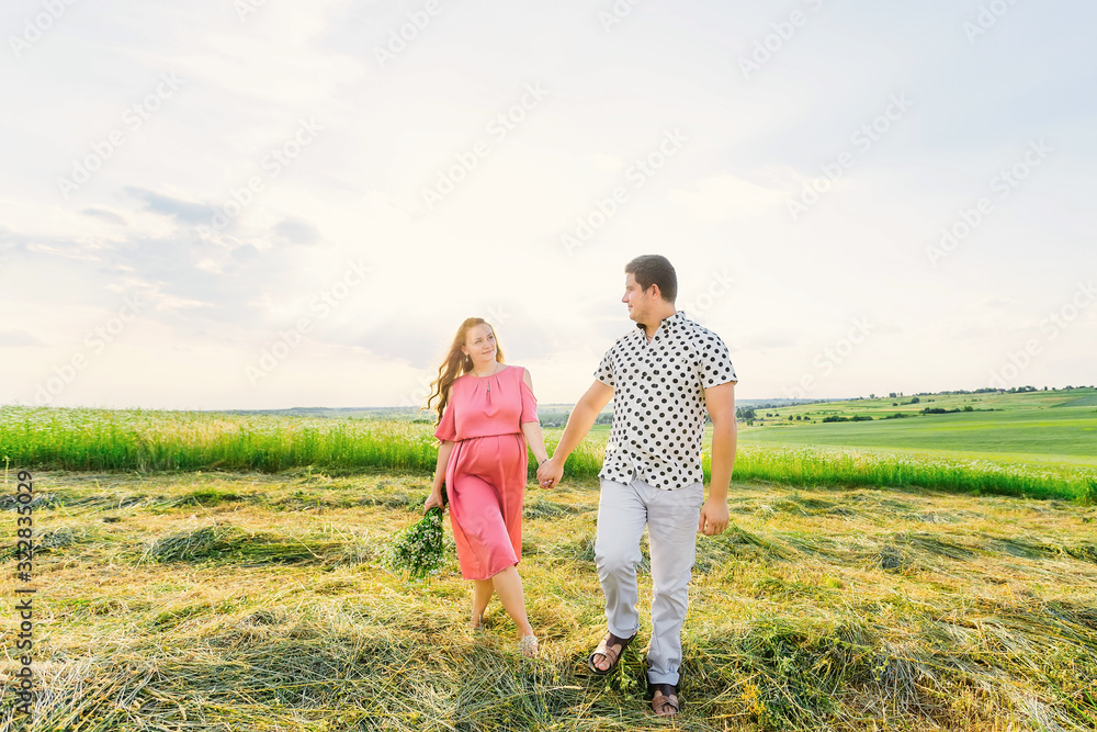 pregnant woman in a pink dress holds a bouquet of flowers. expec