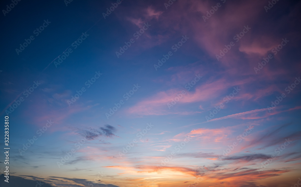 Blue sky during dawn with purple scattered clouds and orange sunset