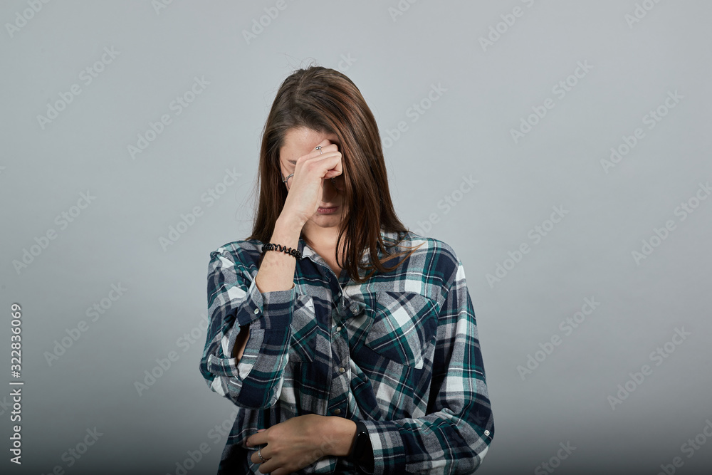 Young brunette girl blue green in checked shirt on grey background upset woman in glasses with bad mood Young brunette girl blue green in checked shirt on grey background upset woman in glasses with bad mood