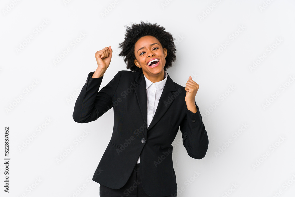 Middle aged african american business woman against a white background isolated celebrating a special day, jumps and raise arms with energy. Middle aged african american business woman against a white background isolated celebrating a special day, jumps and raise arms with energy.
