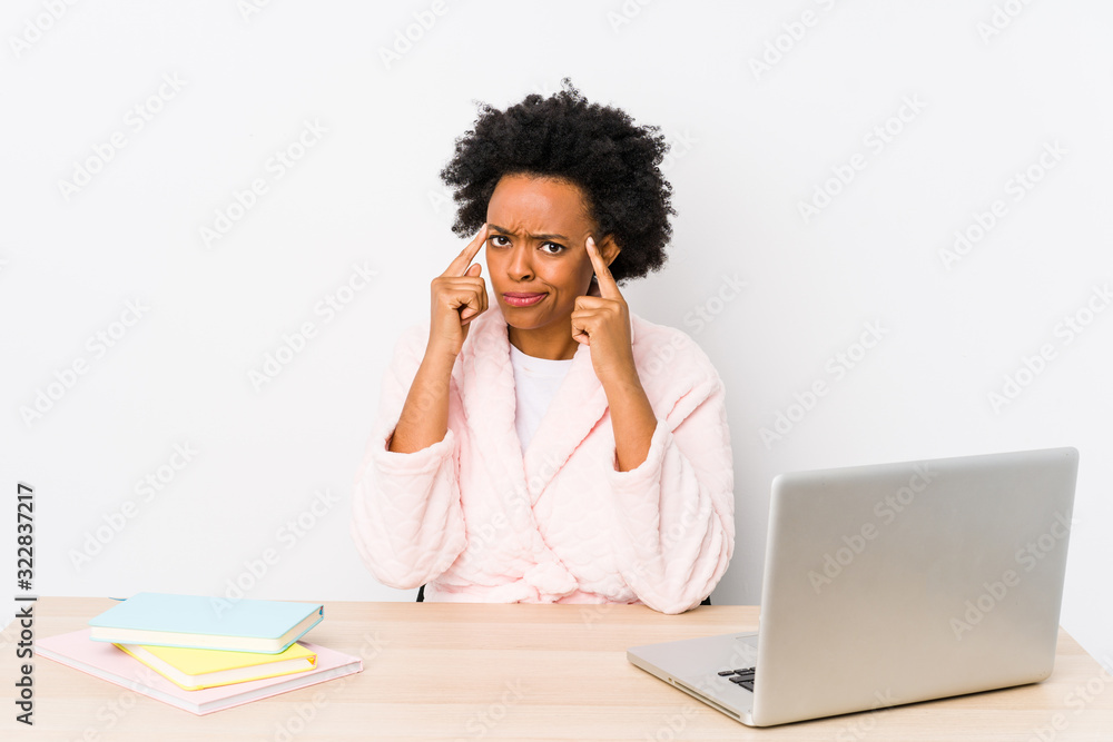 Middle aged african american woman working at home isolated focused on a task, keeping forefingers pointing head. Middle aged african american woman working at home isolated focused on a task, keeping forefingers pointing head.