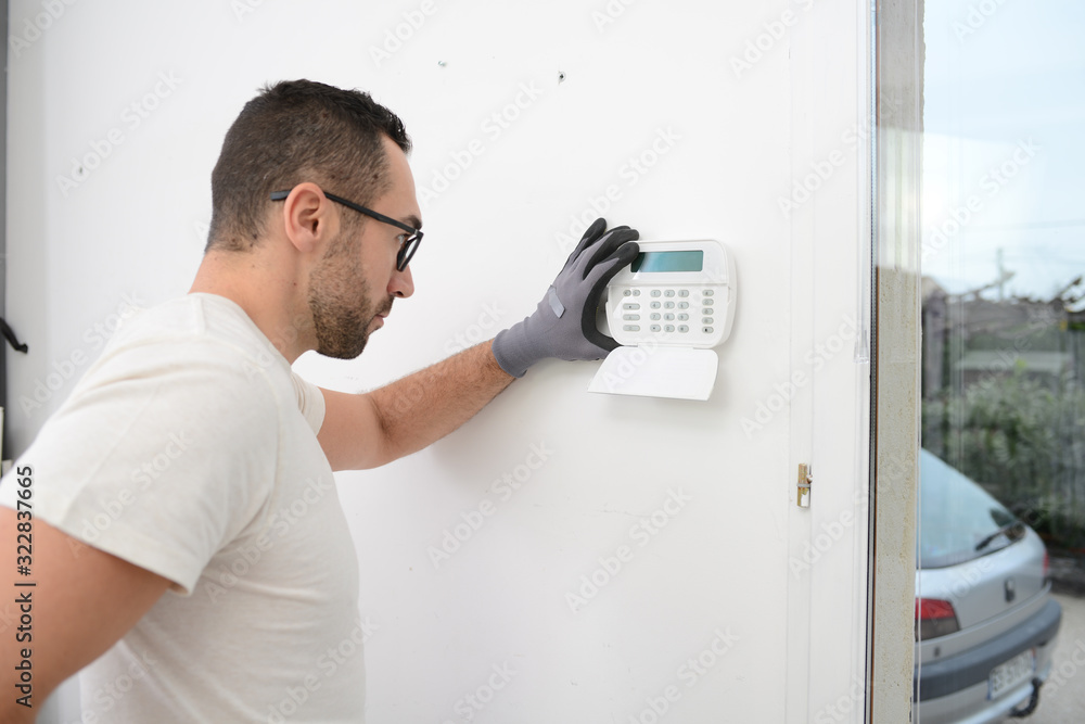 handsome man worker installing alarm technology insurance in home for burglar prevention