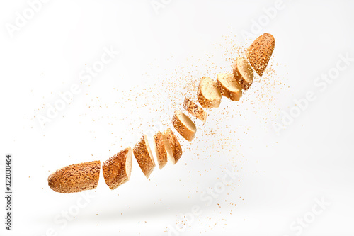 Baguette with sesame seed flying in air. Fresh baked bread sliced, cut. Traditional bakery product french baguette. Delicious crispy wheat bread, levitation, fly food concept photo
