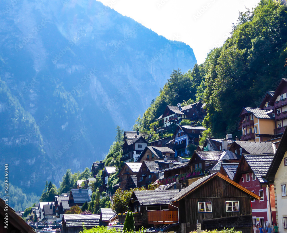 A small village located by the lake in Hallstatt, Austria. The houses have many different colors. Alpine village. Idyllic landscape. Coexistence of human and nature. High mountains around